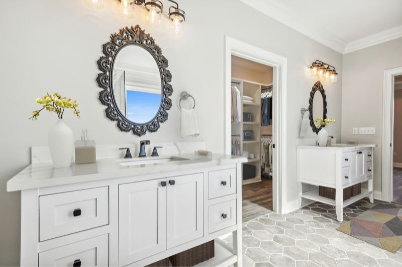 Bathroom with white cabinets, decorative mirrors, and hexagon tile floor.