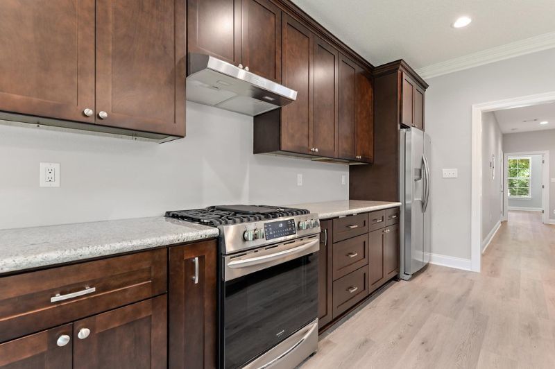 Dark brown kitchen cabinets with stainless steel appliances and light countertops.