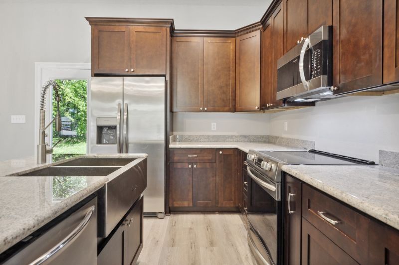 Kitchen with dark wood cabinets, stainless steel appliances, granite countertops, and a door to the outdoors.