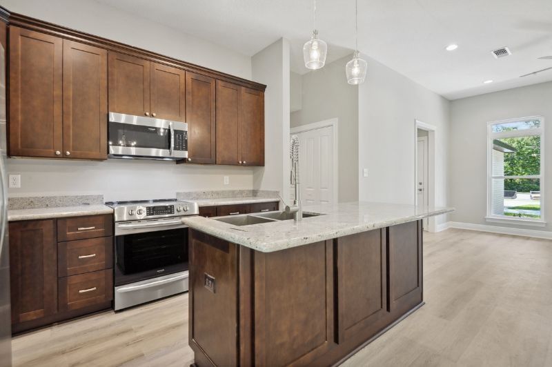 A modern kitchen with dark wood cabinets, stainless steel appliances, and a white island.