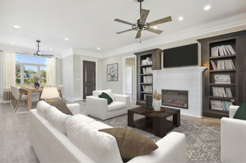 Spacious living room with white sofas, fireplace, and bookshelves. Dining area visible.