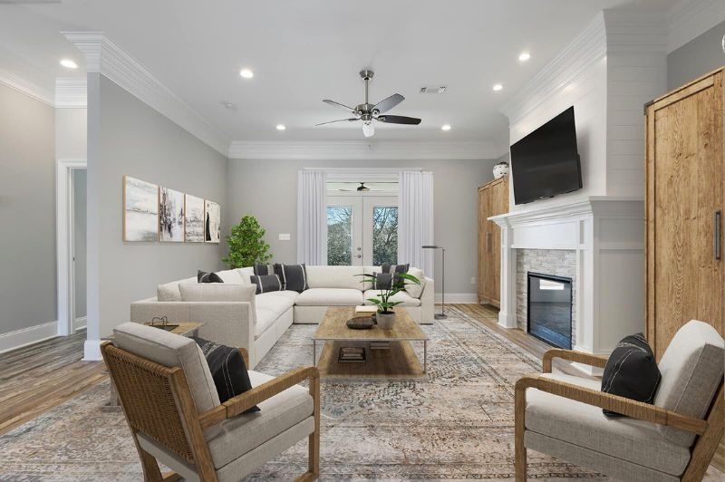 Spacious living room with sectional sofa, fireplace, and French doors. Neutral colors, with wood accents.