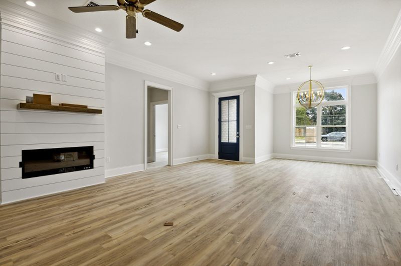 Empty living room with wood floors, fireplace, and chandelier.