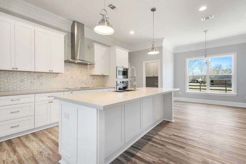 White kitchen with island, cabinets, stainless steel appliances, and wood flooring.