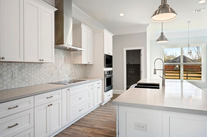 White kitchen with island, cabinets, stainless steel appliances, and window with outdoor view.