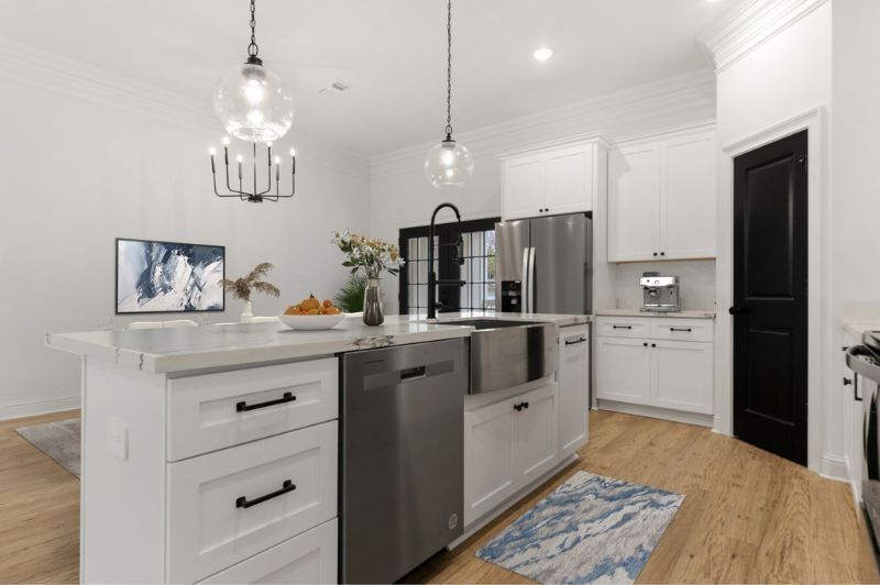 Modern white kitchen with island, stainless steel appliances, and black accents.