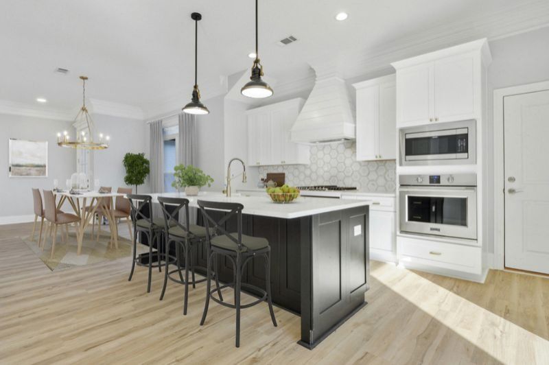 Modern kitchen with white cabinets, dark island, and dining area.