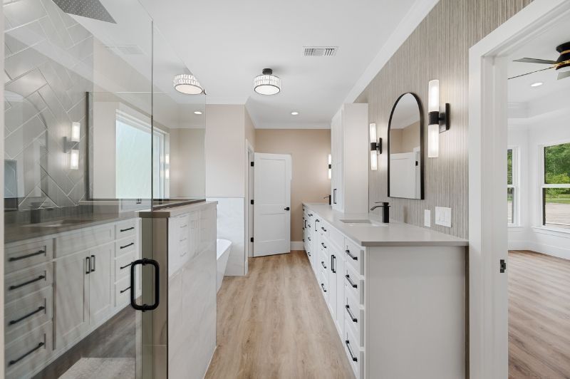 Modern bathroom with white cabinets, gray countertops, glass shower, and light wood-look floors.