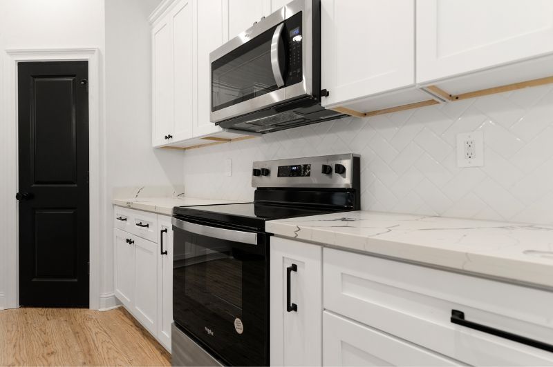 White kitchen with black appliances, cabinets, and door.