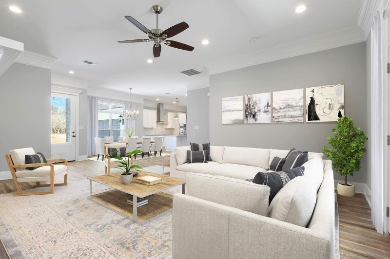 Living room with sectional sofa, artwork, and a coffee table; light blue walls, hardwood floor.