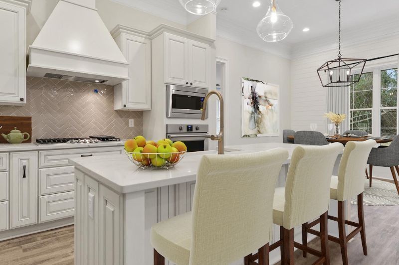 White kitchen with island seating and dining area.