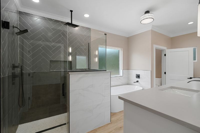 Modern bathroom with glass shower, white marble, and light wood flooring.