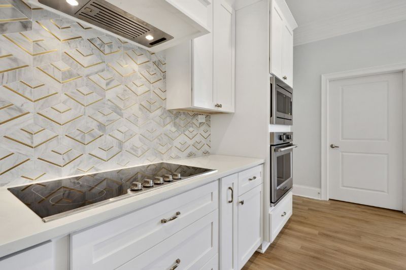 White kitchen with marble backsplash, gold accents, and built-in oven.