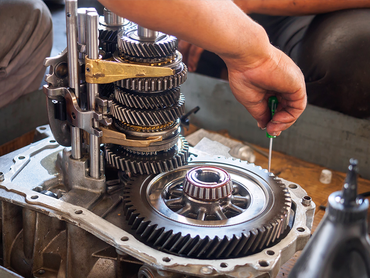 A man is working on a gearbox with a screwdriver