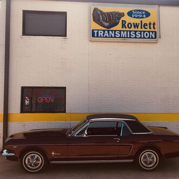 A brown car is parked in front of a rowlett transmission store