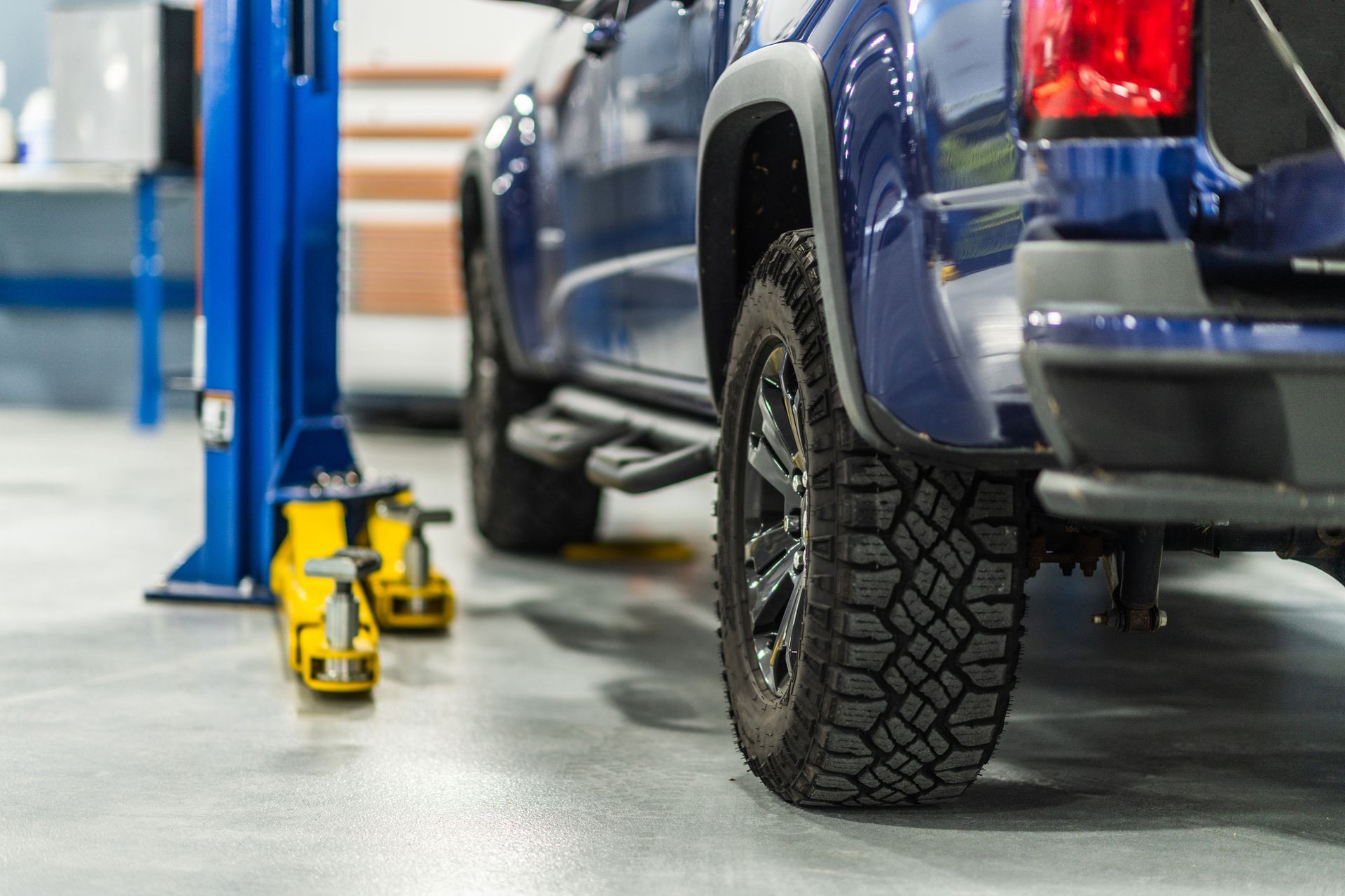 A blue truck is sitting on a lift in a garage.