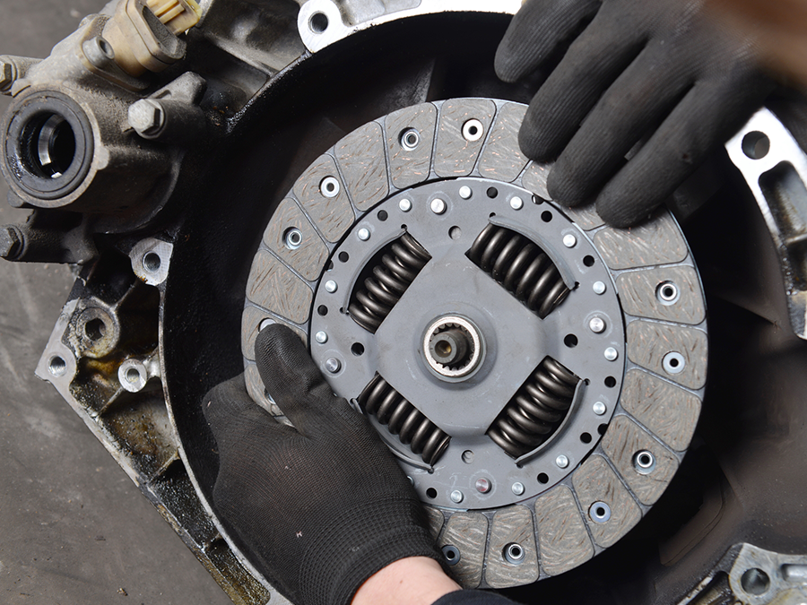 A person wearing black gloves is holding a clutch plate
