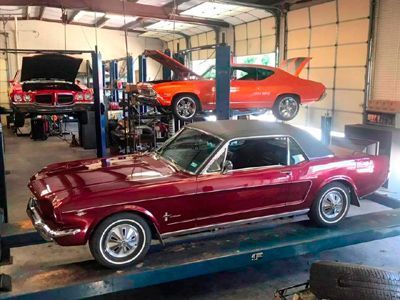 A red mustang is parked on a lift in a garage.