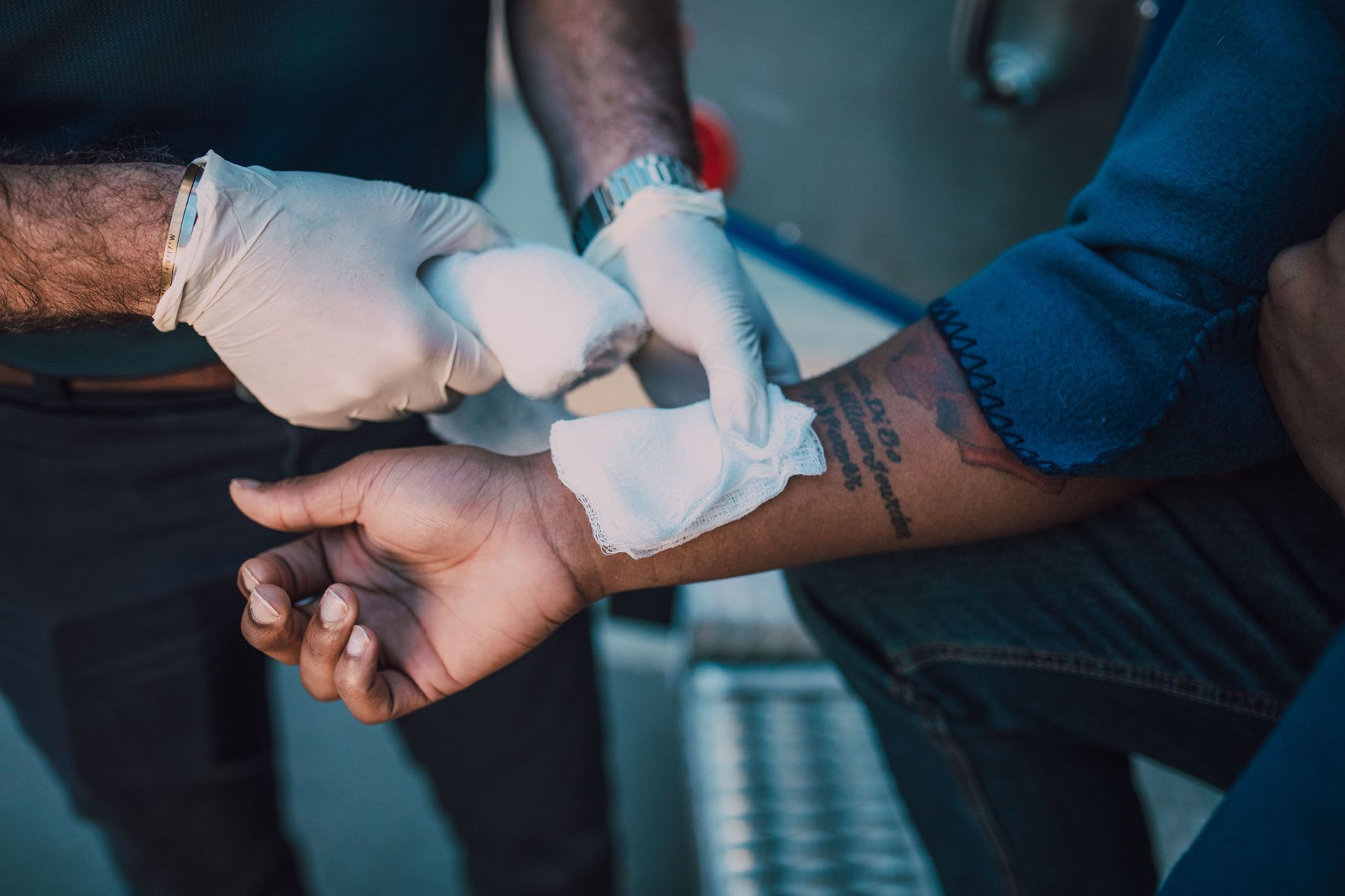 Healthcare worker bandaging a person’s forearm with white gauze and gloves