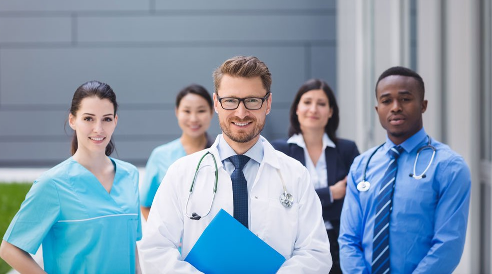 A group of doctors and nurses are standing next to each other in front of a building.