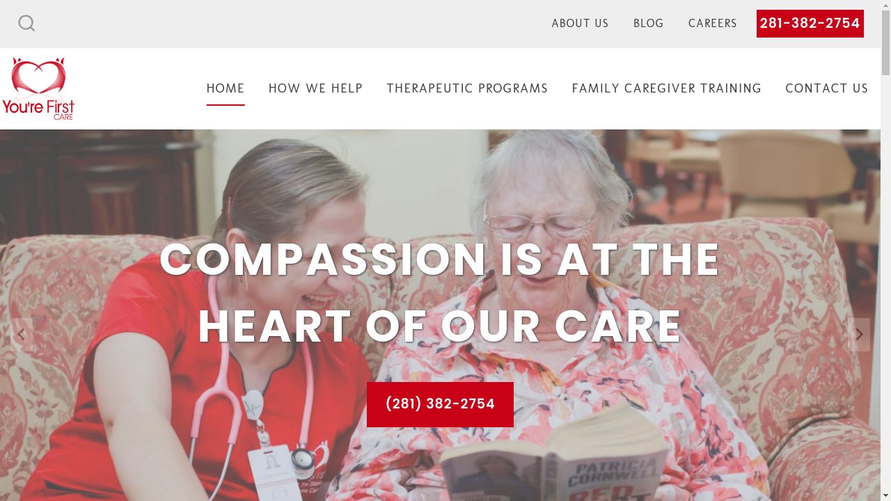 A nurse is sitting next to an elderly woman on a couch reading a book.