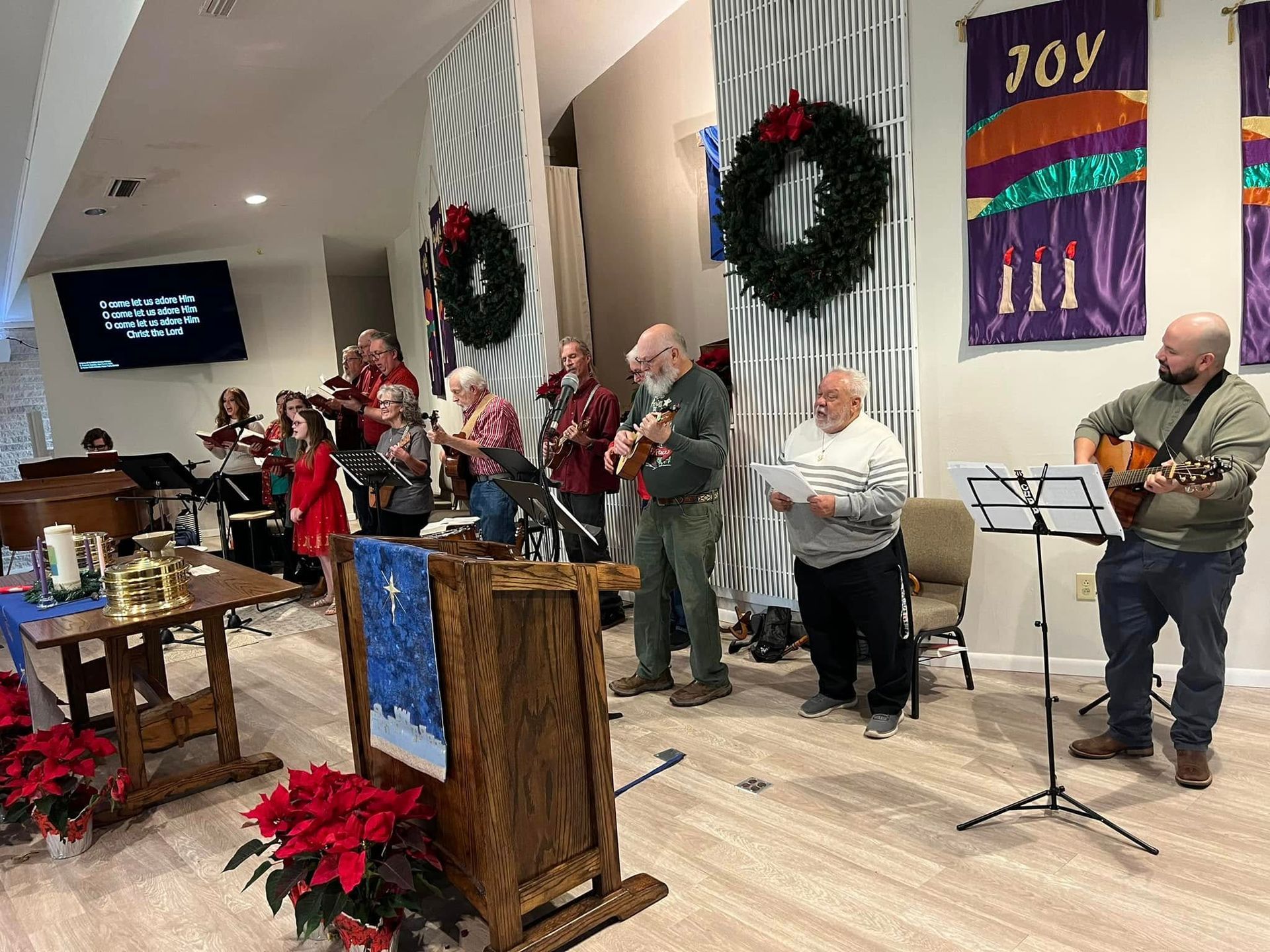 Group of musicians playing instruments in a church decorated for Christmas.