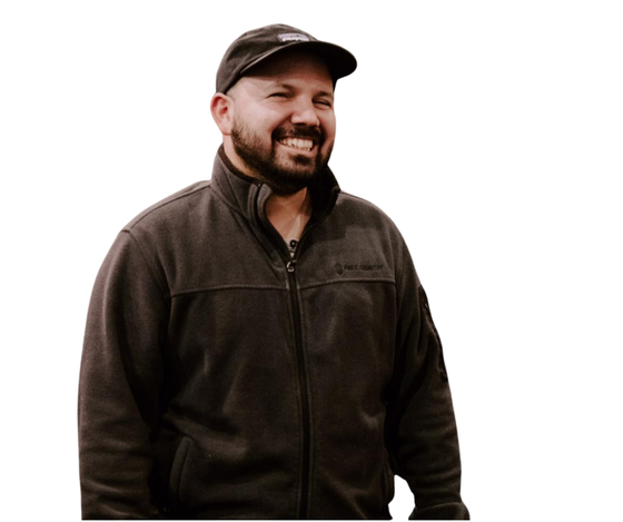 Man wearing a black cap and jacket, smiling.