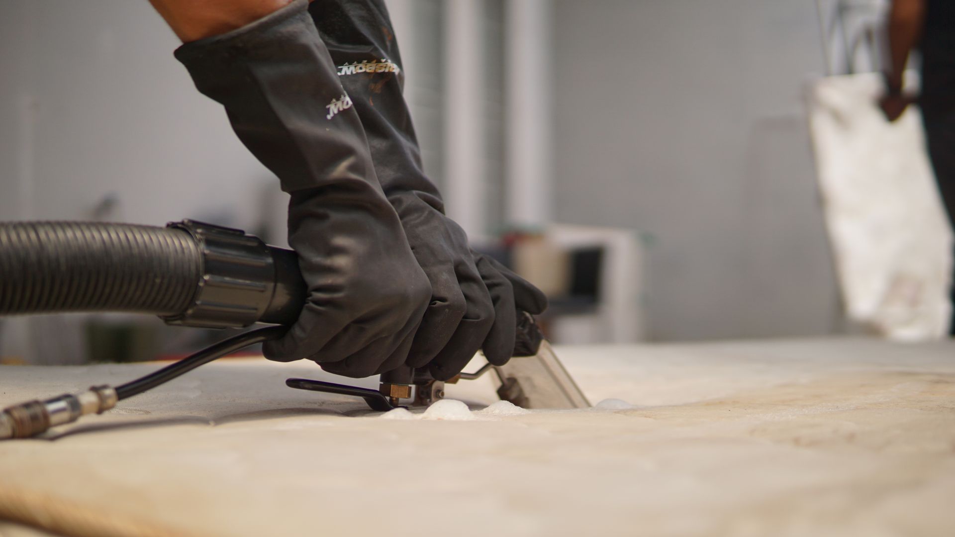 A person is using a vacuum cleaner to clean a carpet.