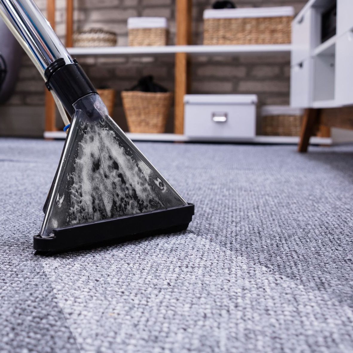 A vacuum cleaner is cleaning a carpet in a living room.