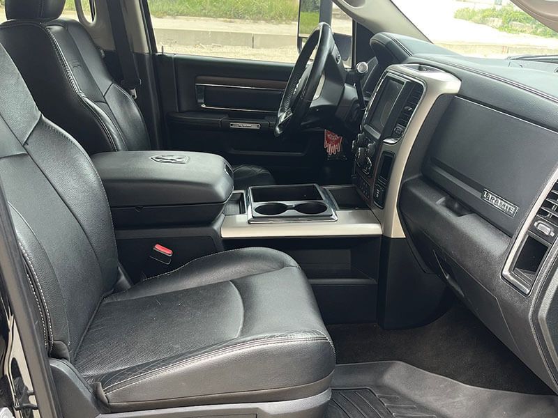 Black leather interior of a truck, showing seats, console, dashboard, and steering wheel.