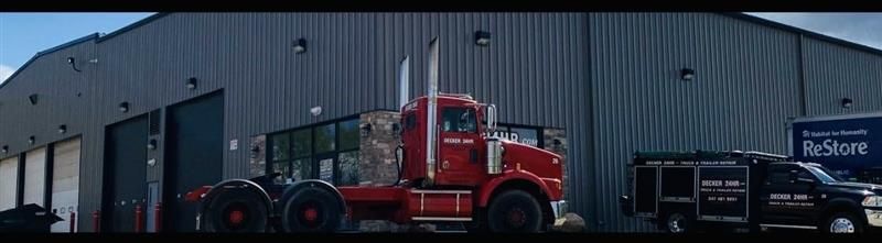 Red semi-truck in front of gray warehouse. Black truck and sign for ProStore nearby.