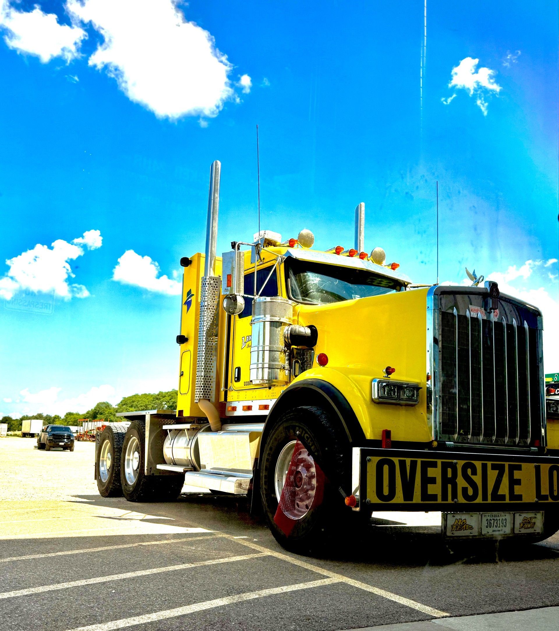 Yellow oversized semi-truck parked in a lot under a bright blue sky. Yellow oversized semi-truck parked in a lot under a bright blue sky.