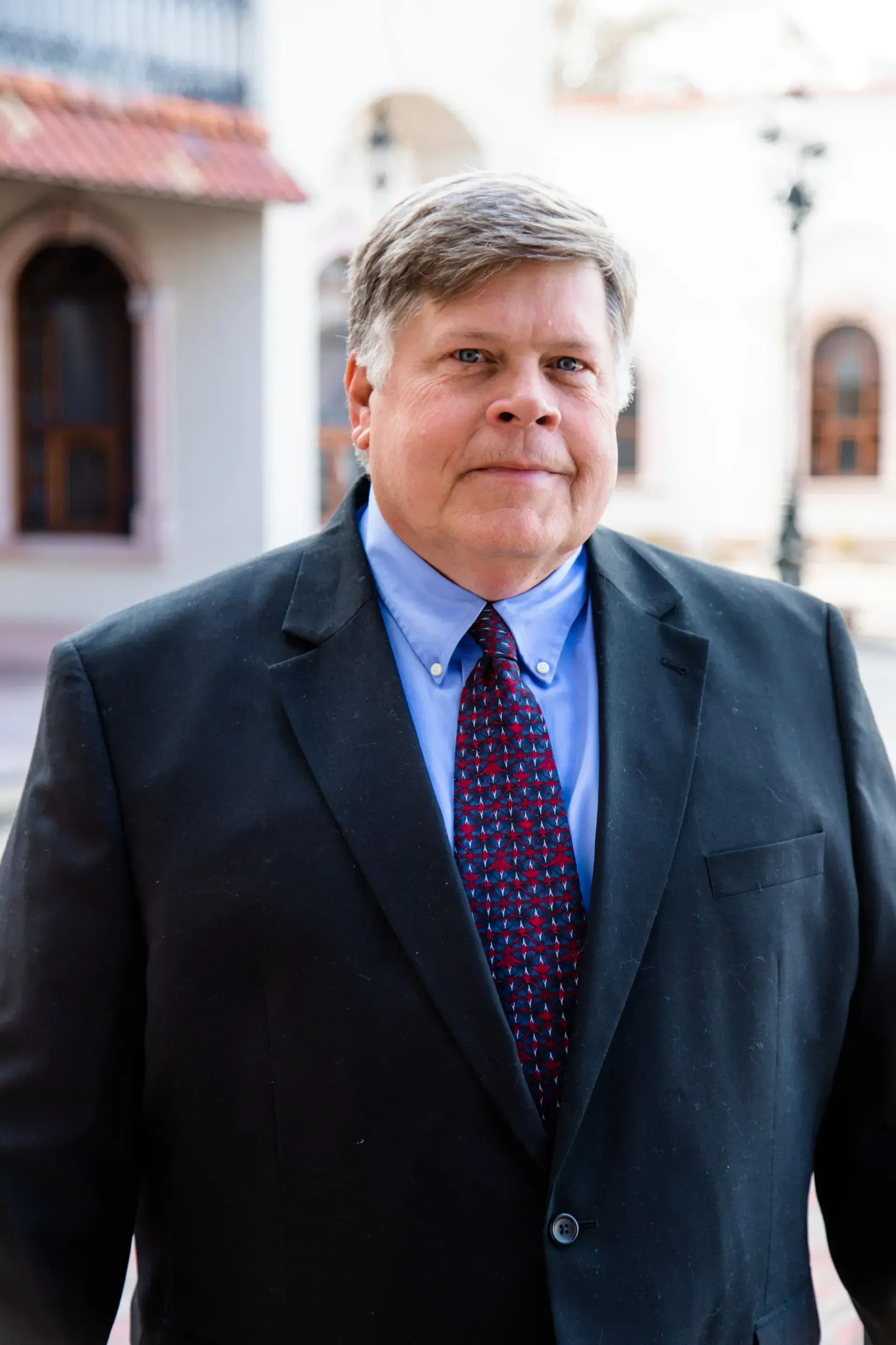 A man in a suit and tie is standing in front of a building.