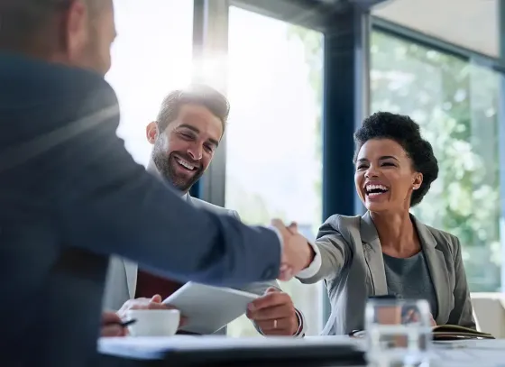 Business meeting with smiling colleagues shaking hands across a conference table