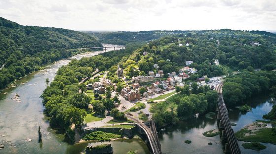 Aerial view of a riverside village surrounded by lush green forest and winding water channels.