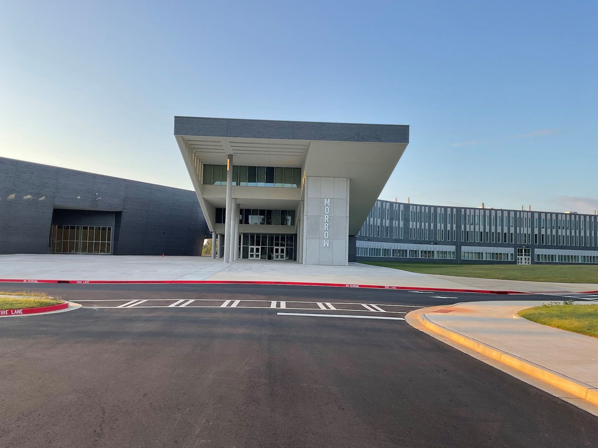 A large building with a lot of windows is sitting next to a road.