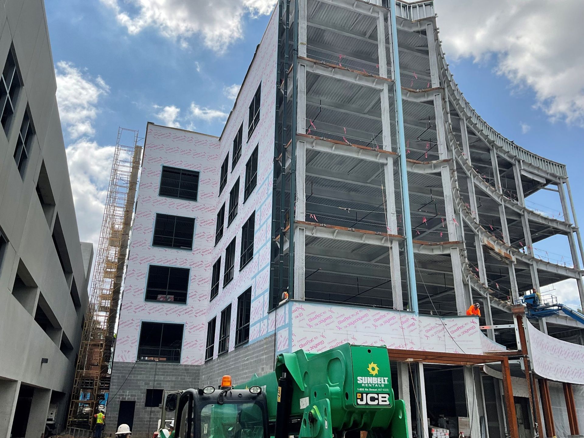 A large building under construction with a green crane in front of it.