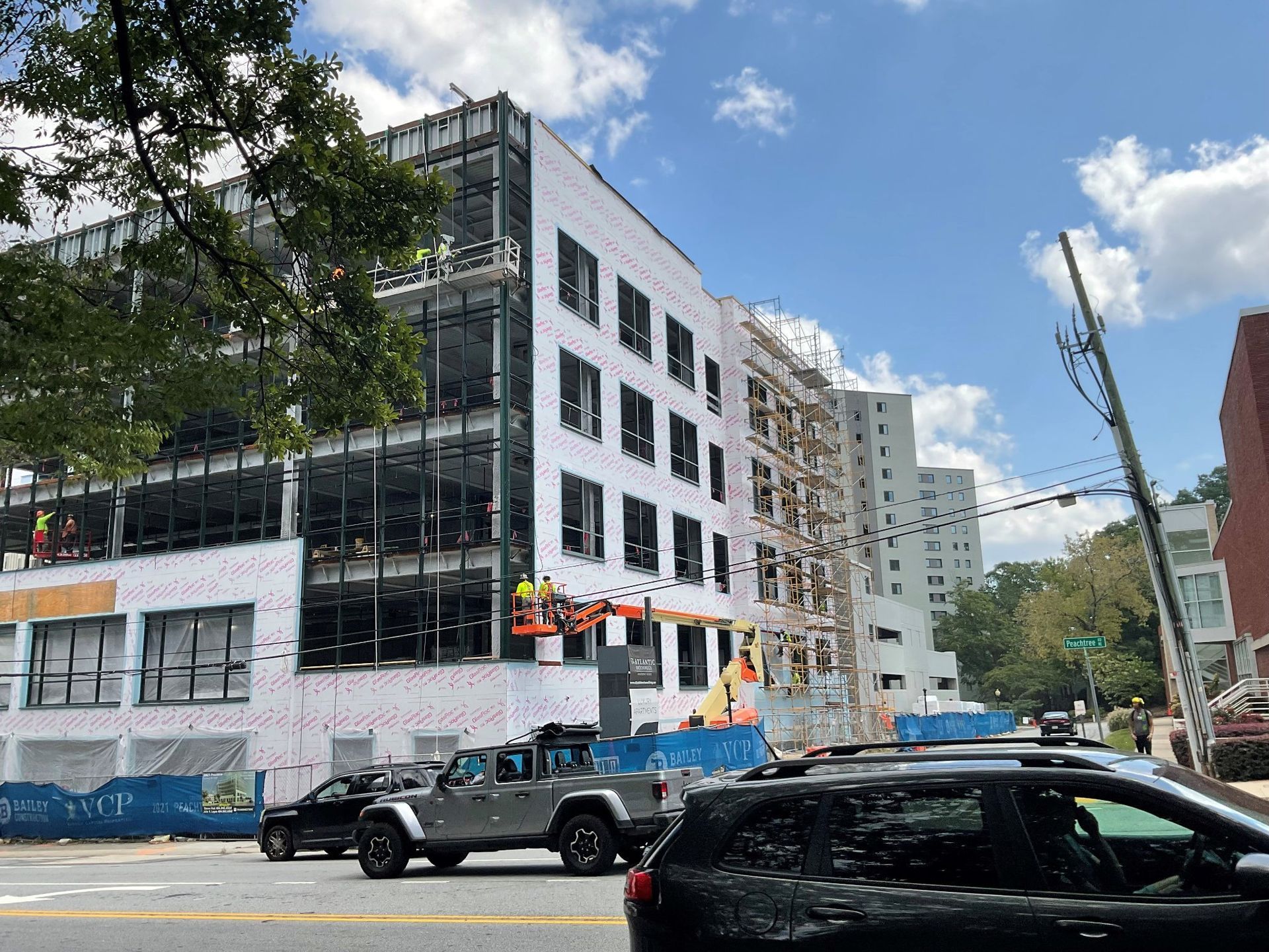 A car is parked in front of a building under construction.