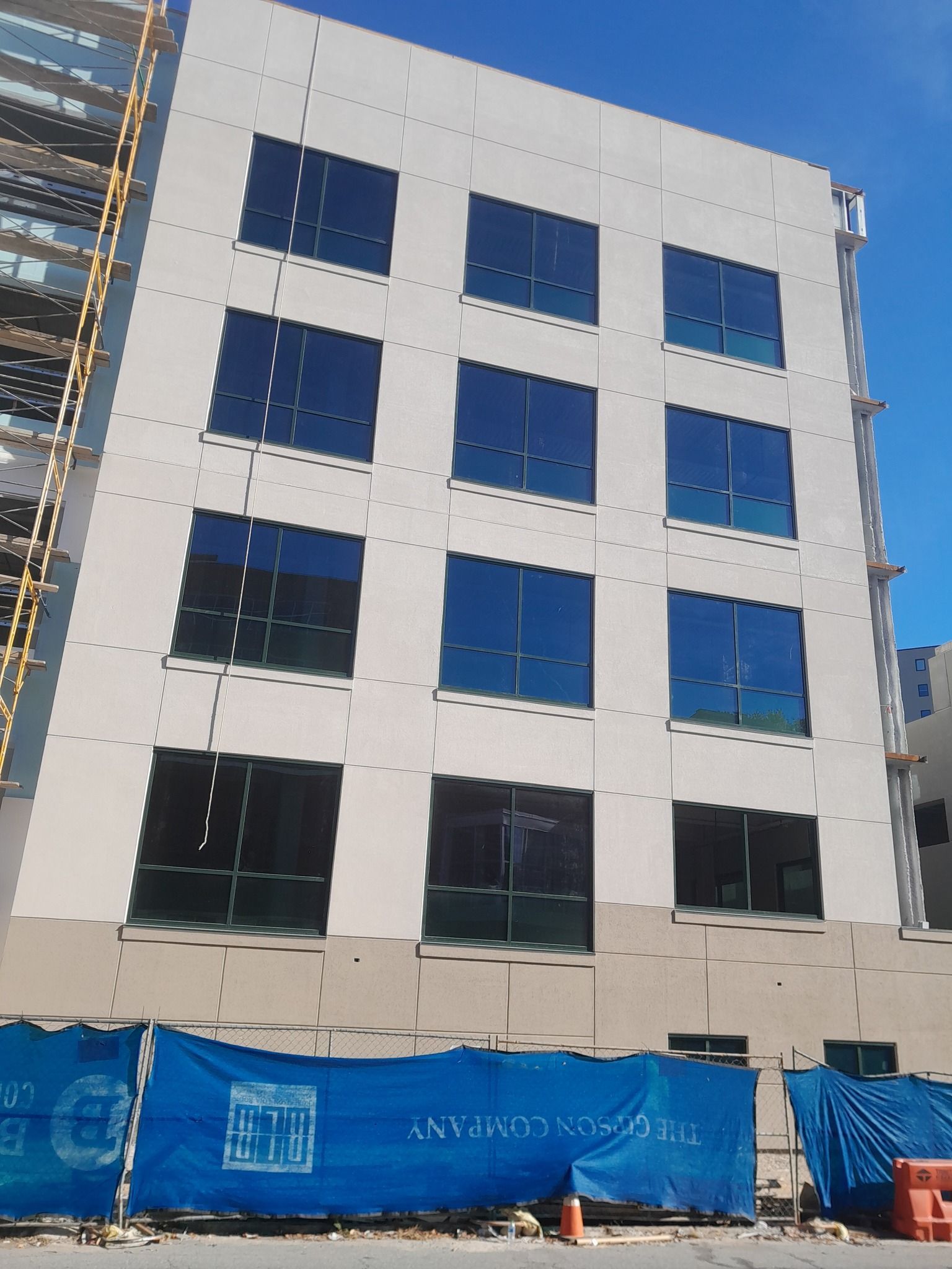 A building under construction with a blue fence in front of it