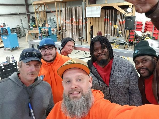 A group of men are posing for a picture in a workshop.