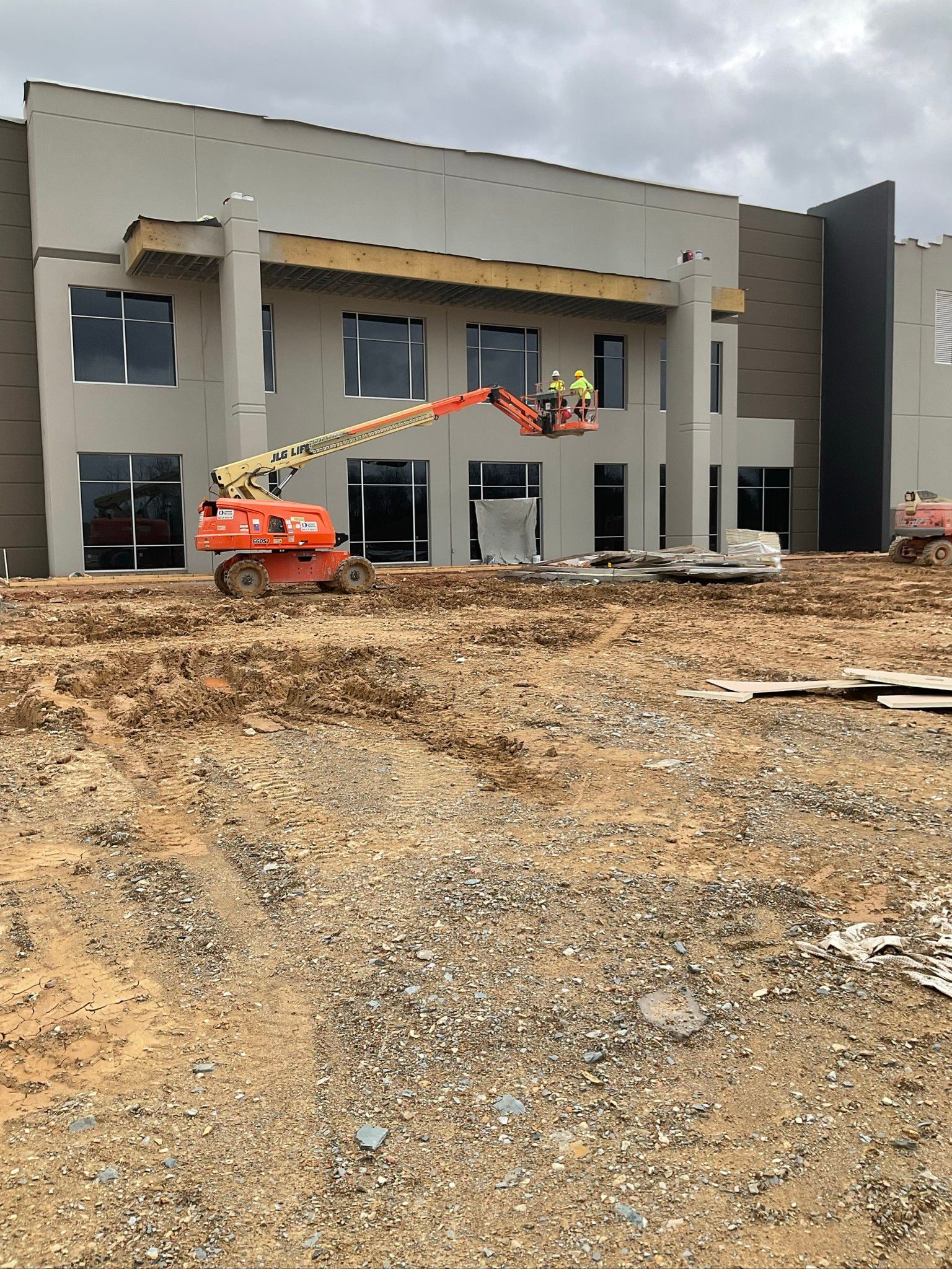 A large building is being built in the middle of a dirt field.