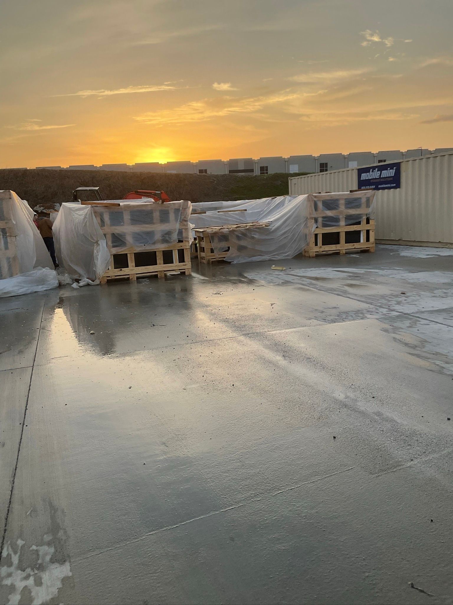 There is a sunset in the background and a lot of crates on the ground.