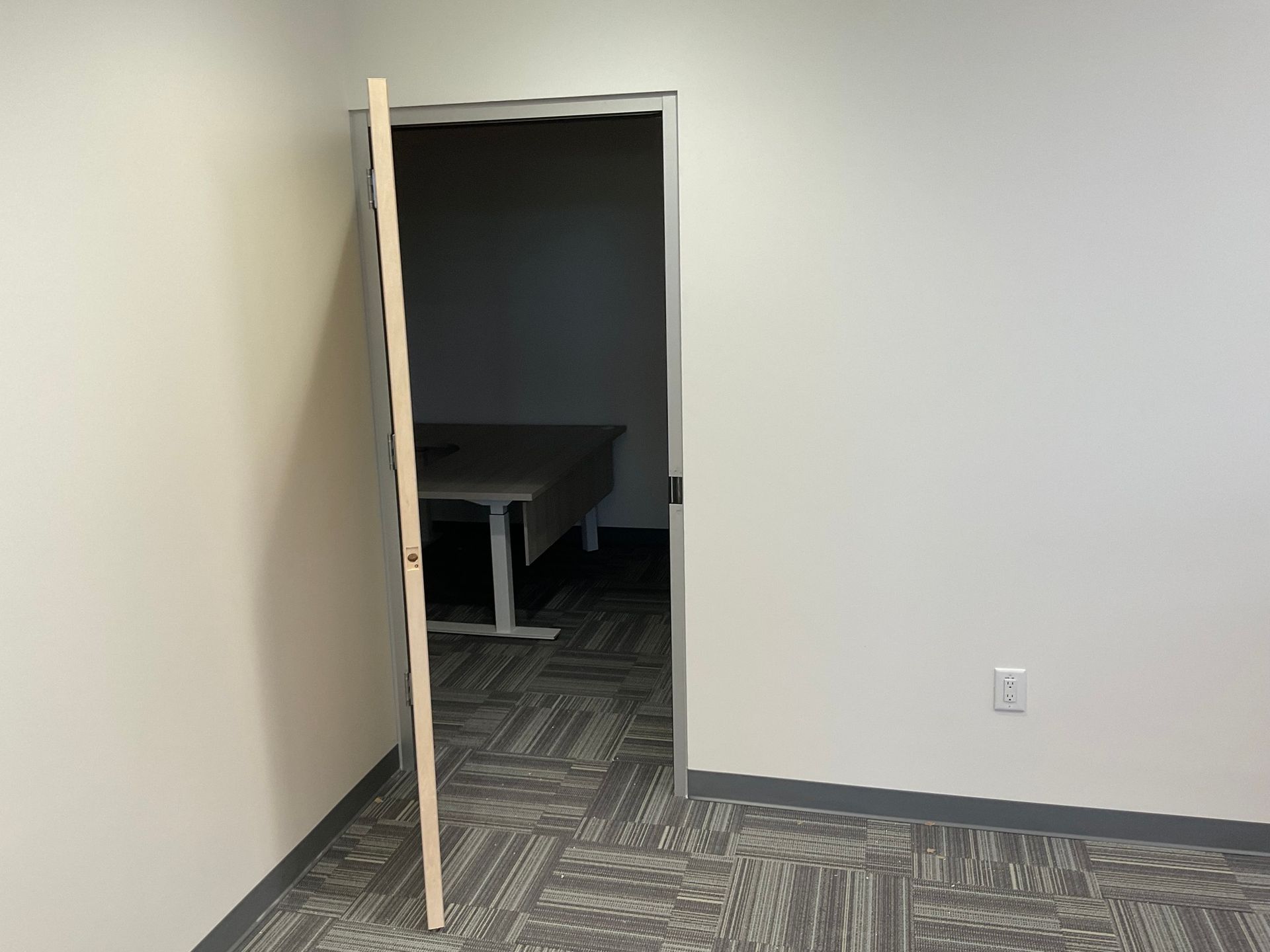 A room with a door open and a desk in it.