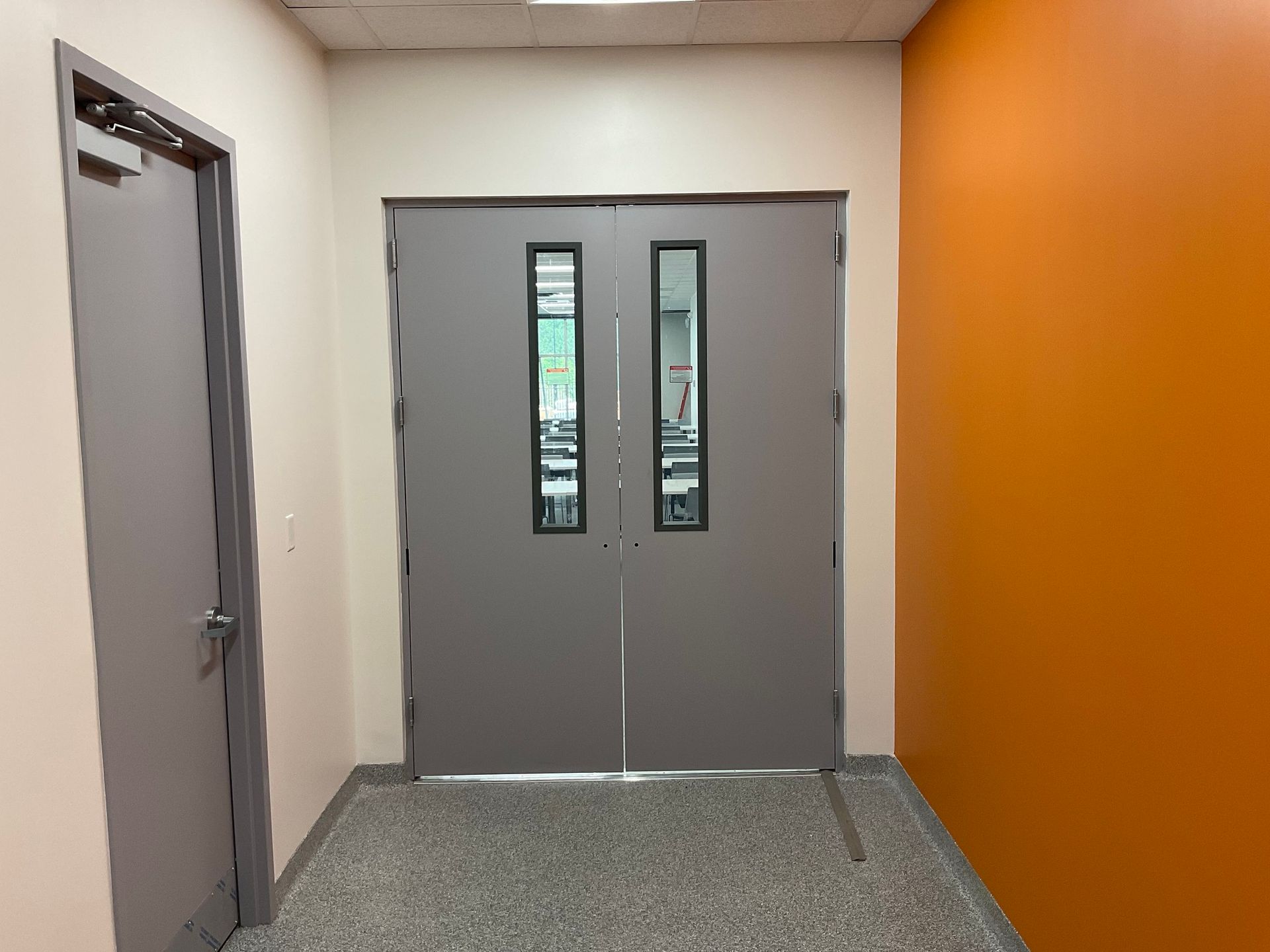 A hallway with two doors and an orange wall