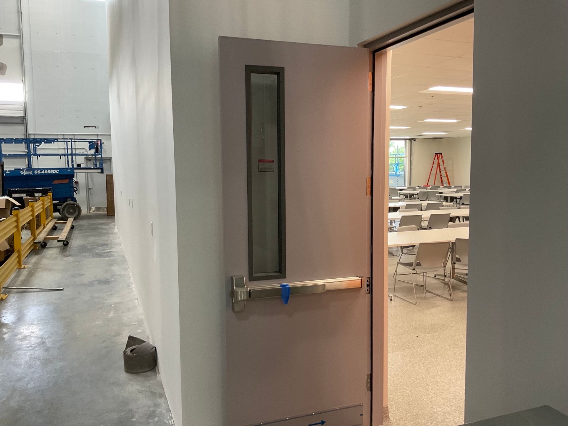 A door is open to a room with tables and chairs in it.
