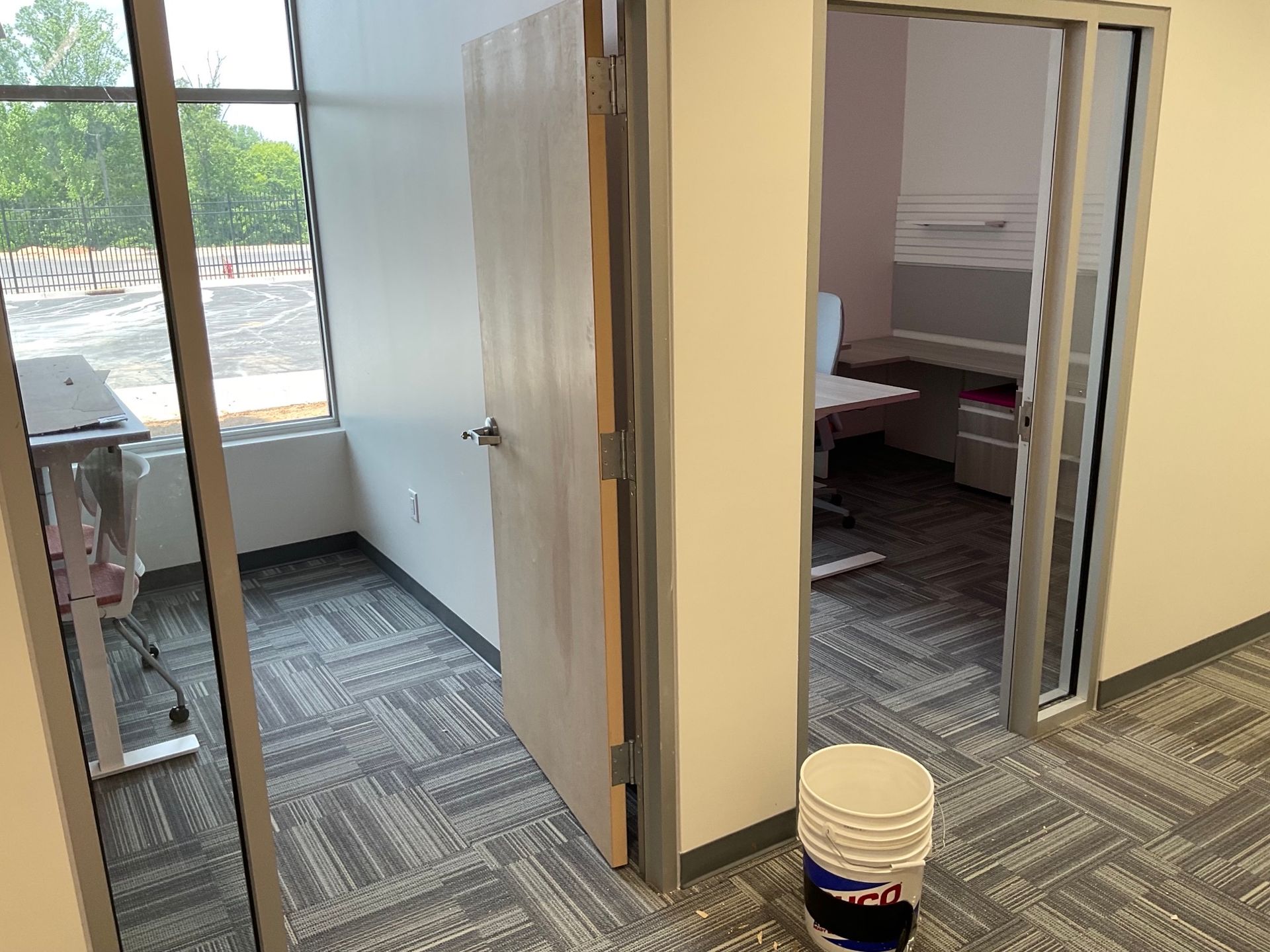 A bucket of paint is sitting in a room next to a door.