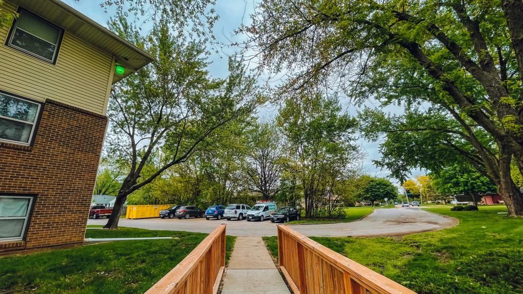 a wooden walkway leading to a building with cars parked in front of it .