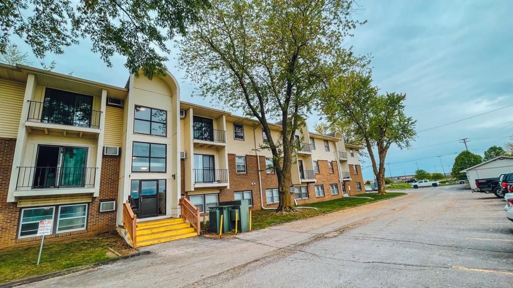 a large apartment building with a parking lot in front of it .