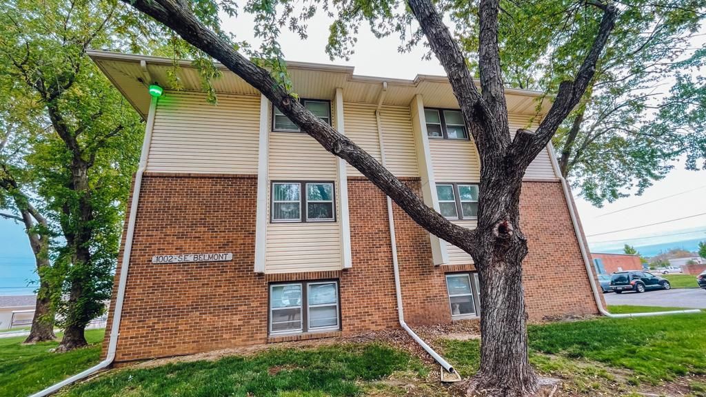 a large brick apartment building with a tree in front of it .
