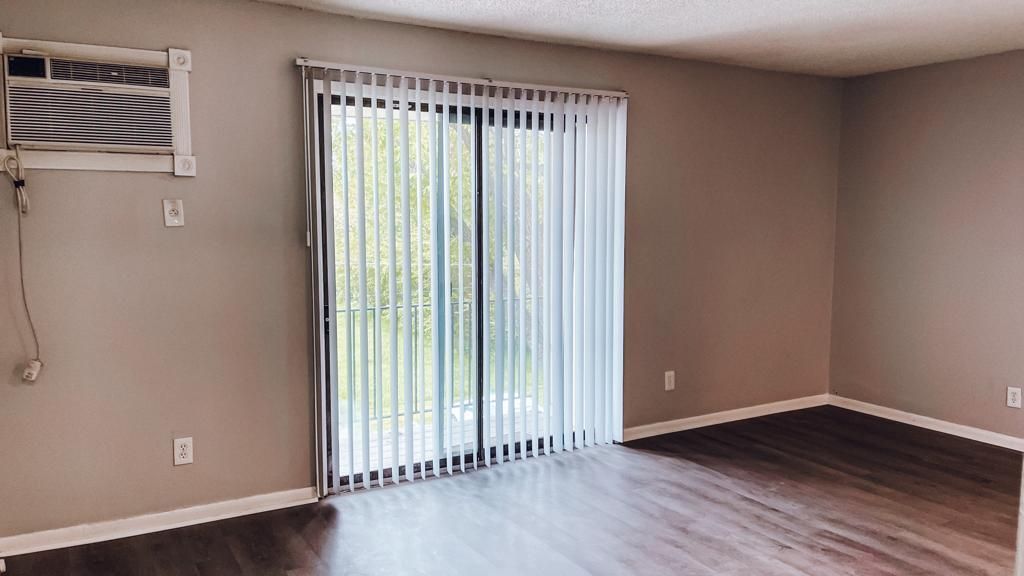 an empty living room with a sliding glass door and blinds .